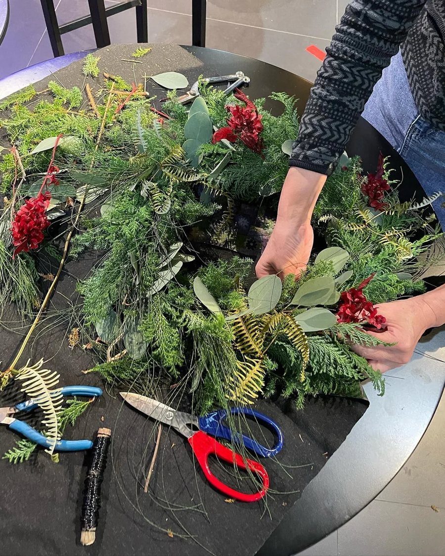 往年手作課現場,桌上鋪滿雪松與葉材,學員正在整理枝葉做聖誕花圈