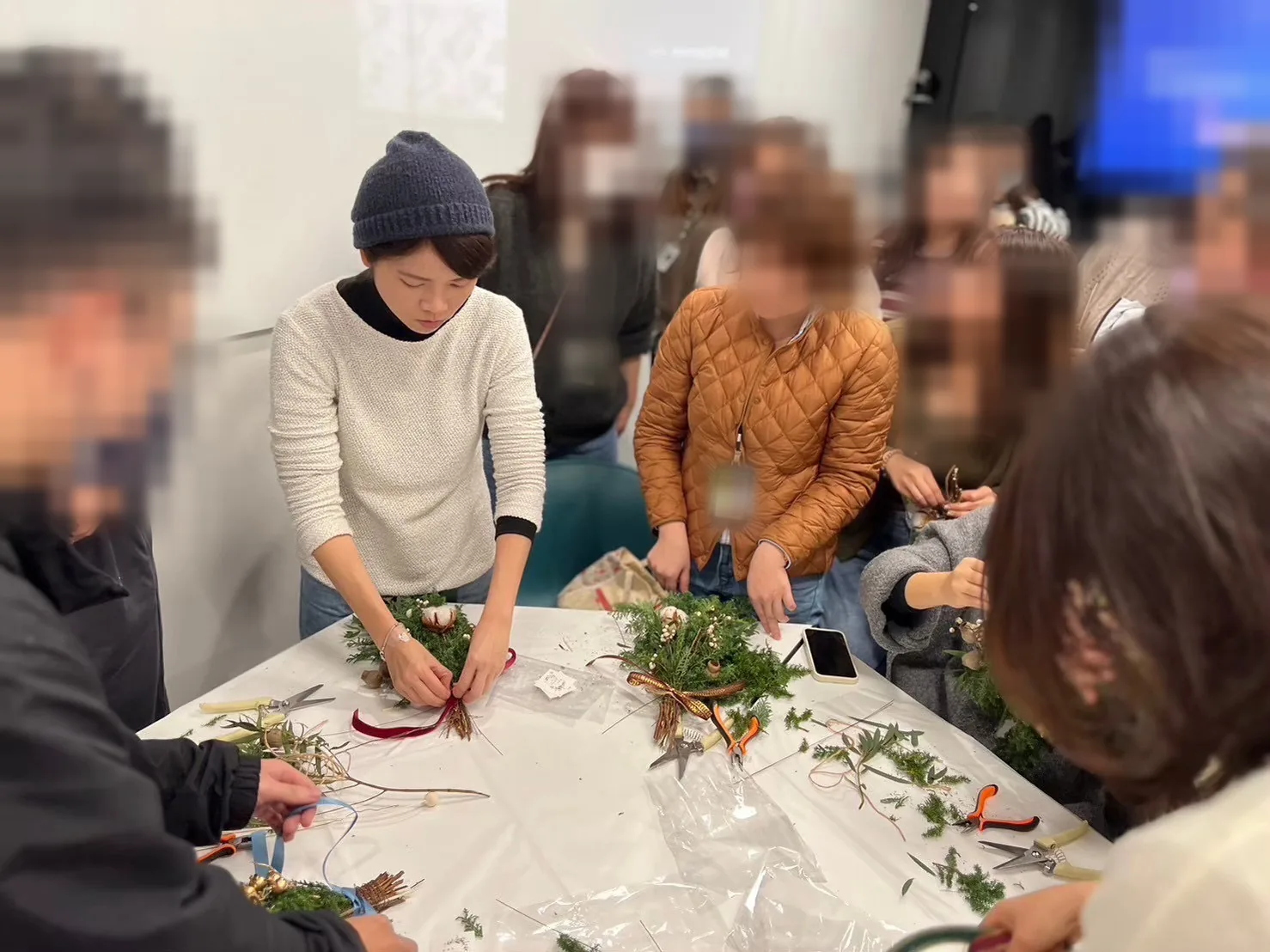 花藝師 Li 在工作桌前整理一束紫白色花束
