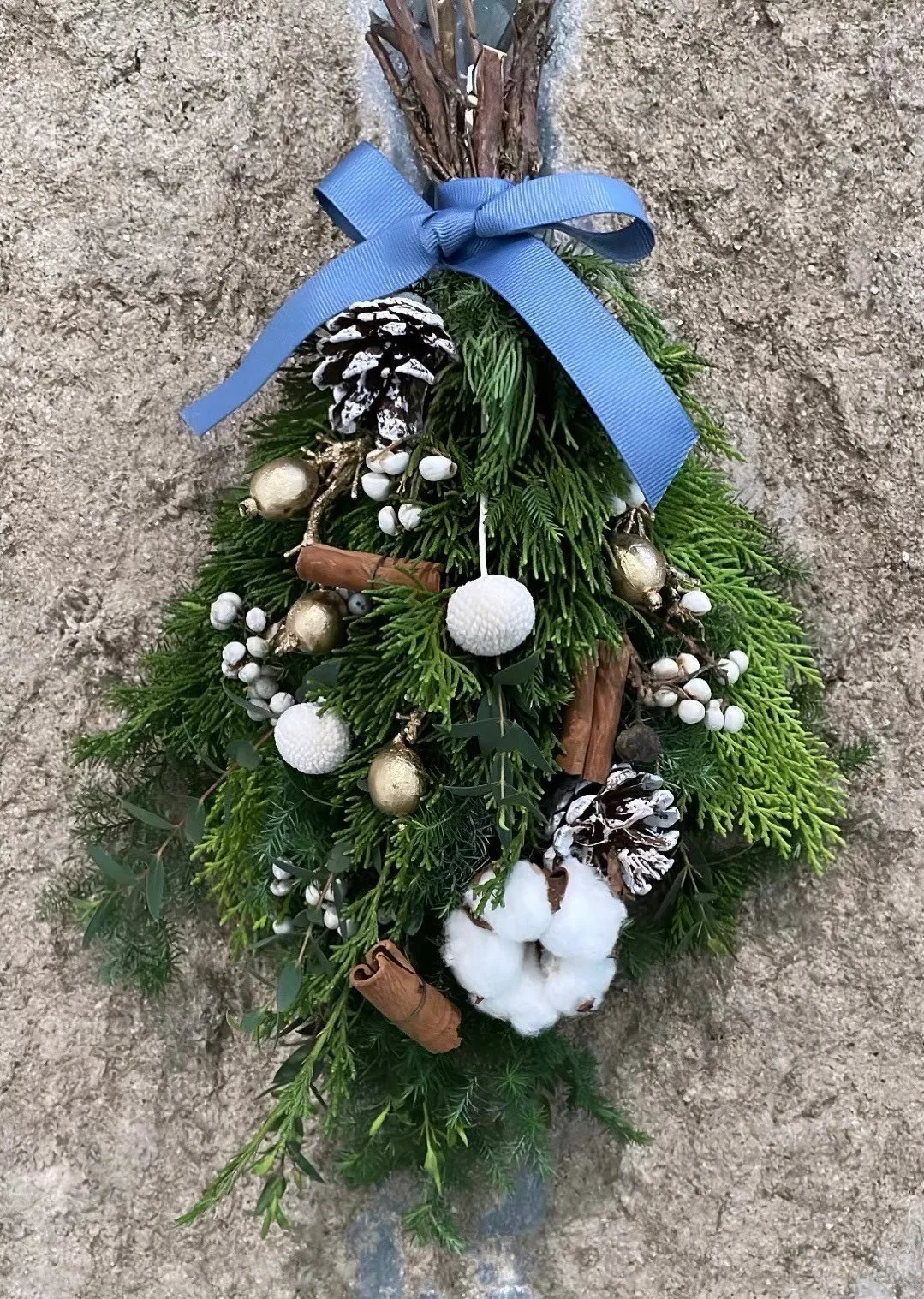綁著藍色緞帶的雪松花束,配松果與棉花